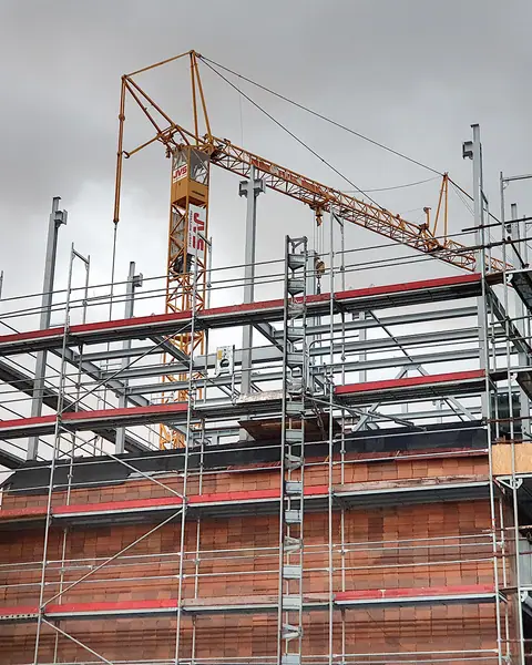 Prédio em obra com andaimes de aço e guindaste